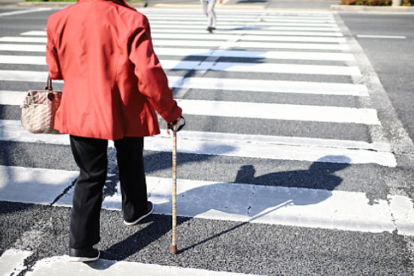 A mature pedestrian crossing the street.