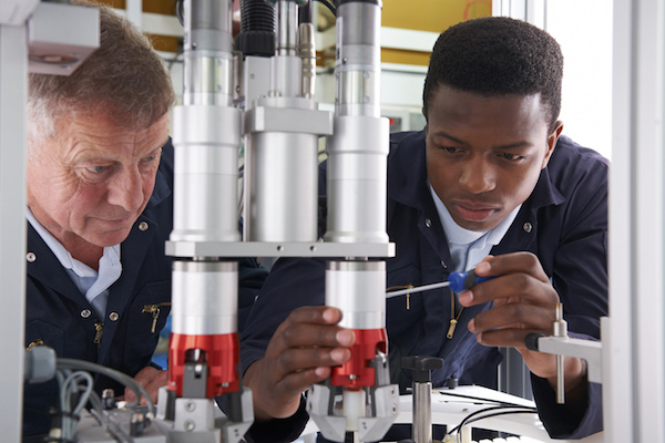 Two men fixing a piece of manufacturing equipment