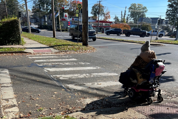 person on a scooter utilizing an ADA accessible crosswalk in a city intersection