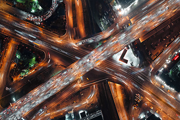 Bird's eye view of a highway running through a city at night with intersections and lights