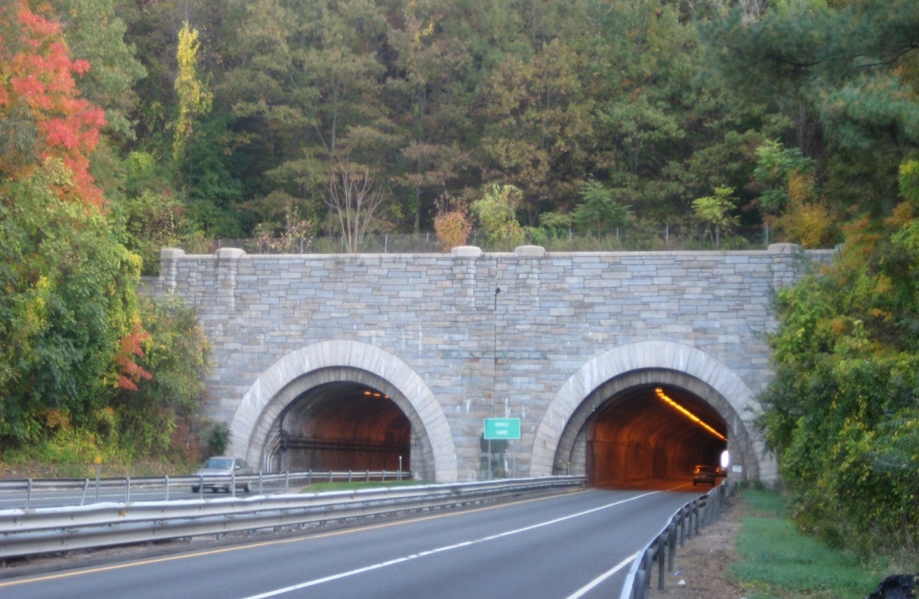 A two-barrel stone tunnel on Route 15 surrounded by lush autumn trees displaying red and green leaves
