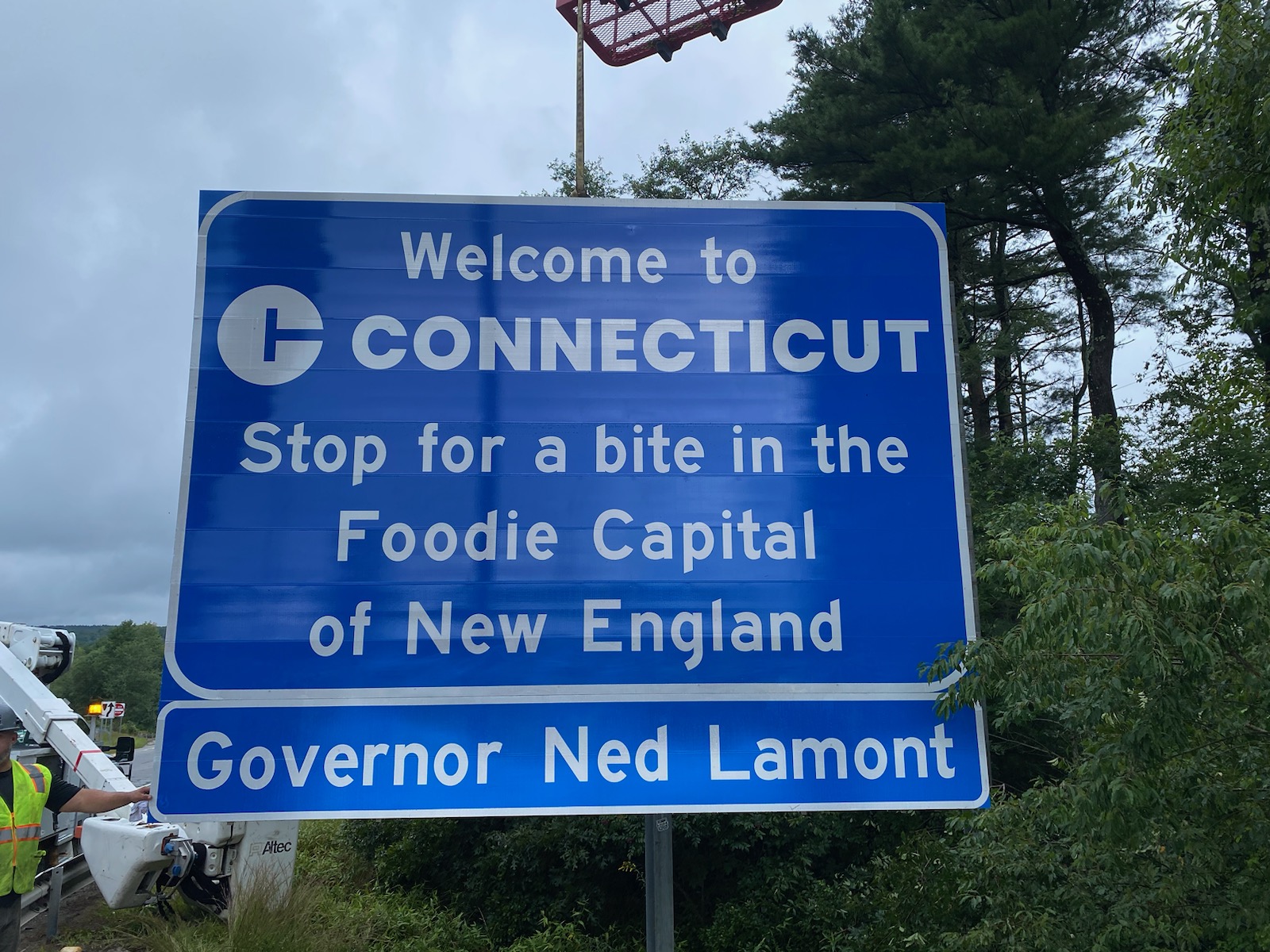 Interstate highway sign that says, "Welcome to Connecticut, Stop for a bite in the Foodie Capital of New England"