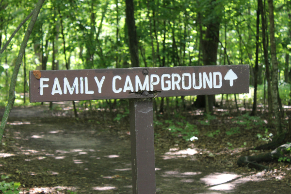 Wood sign in forested area reading "Family Campground" ahead. 