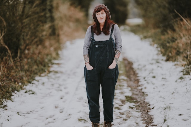middle age woman wearing overalls standing in field