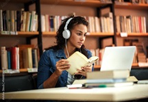 Girl wearing headphones studying in a library