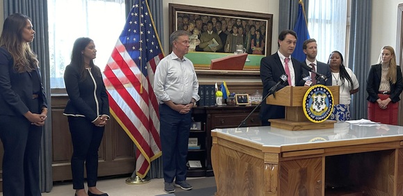 Matthew Brokman speaks during a news conference at the State Capitol. Standing next to him are Governor Lamont and members of the governor’s senior staff.