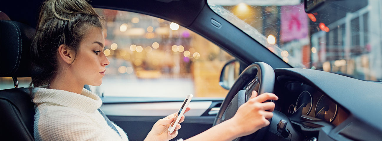 female driver using phone in left hand while driving and not looking at the road - distracted driving