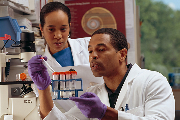 Diverse health professionals in a lab examining test tubes with vaccine results.