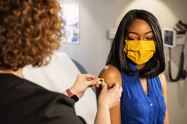 African American woman getting band aid put on after receiving a vaccine.