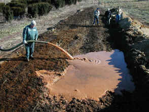 photograph of liquid slurry being pumped into a composting windrow