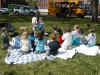Students outside on a blanket listening to teacher at story time 