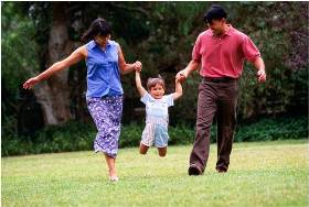 Woman and man outside swinging child between them.