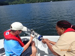 Monitoring Group staff collect a water sample from a lake.