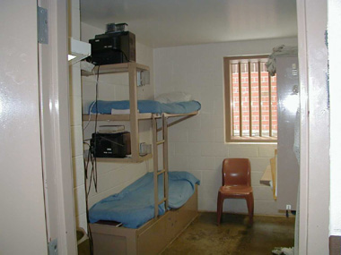 - A typical two person cell with bunk bed, desk toilet and sink.