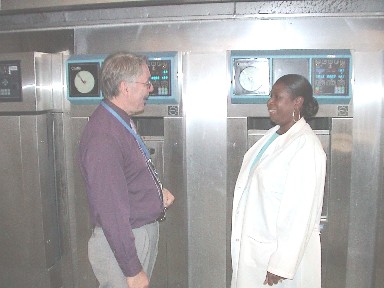 Photo of Gregg Herriford, Section Chief of Administative and Support Services at the State Public Health Laboratory, discussing autoclave procedures with a laboratory assistant.