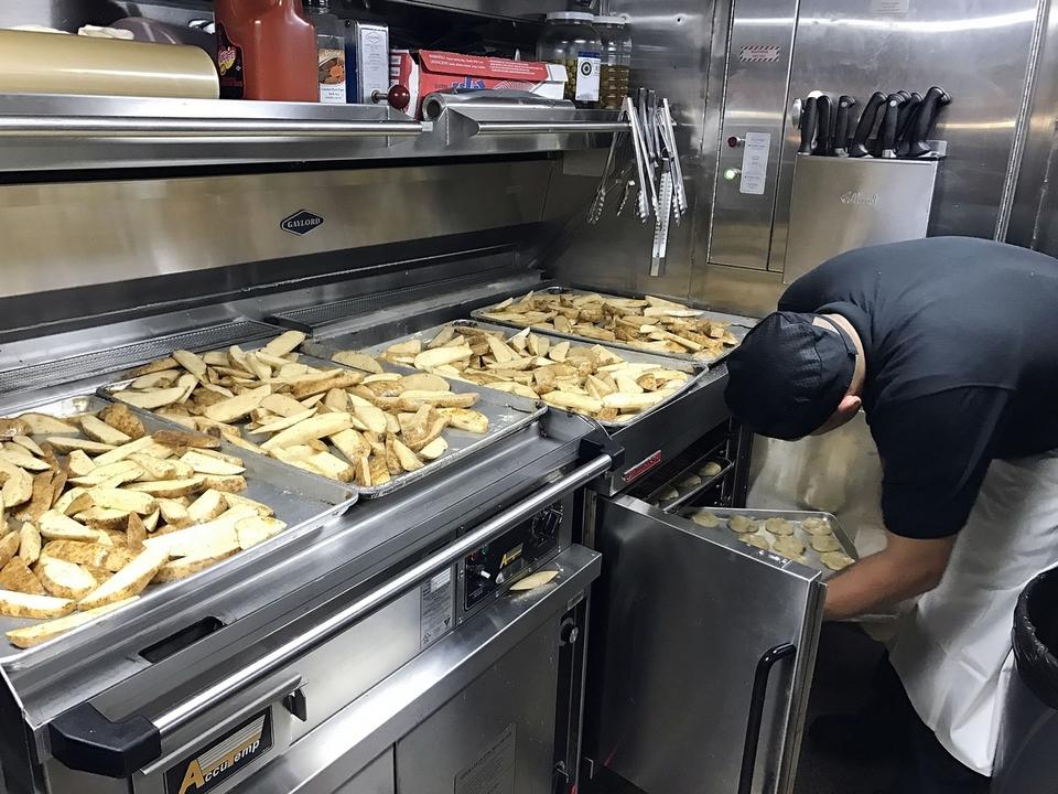 Culinary Specialist 1st Class Alejandro Acosta puts cookies in the oven in the galley aboard the USS John Warner.