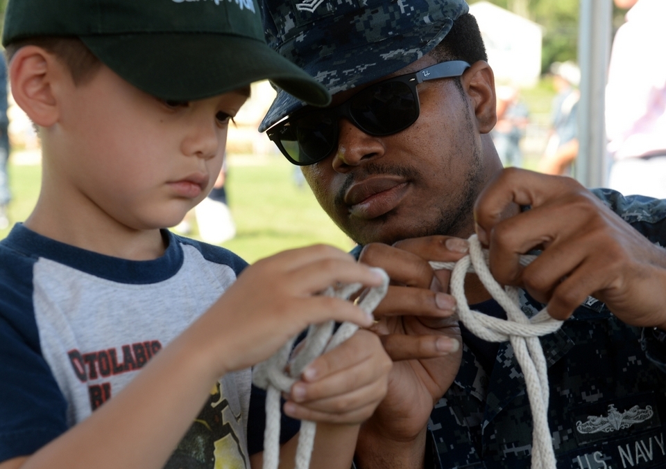 Boatswain Mate Second Class Clement Williams teaches Noah Lind how to tie a sailor knot