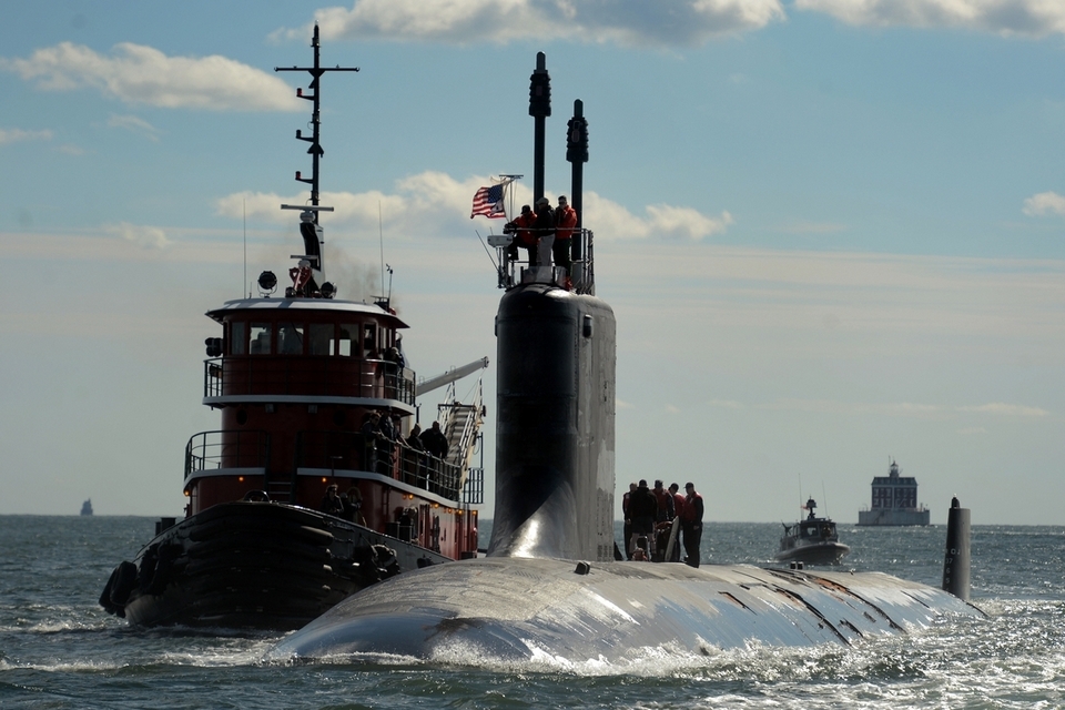 The tugboat guides the USS California up the Thames River