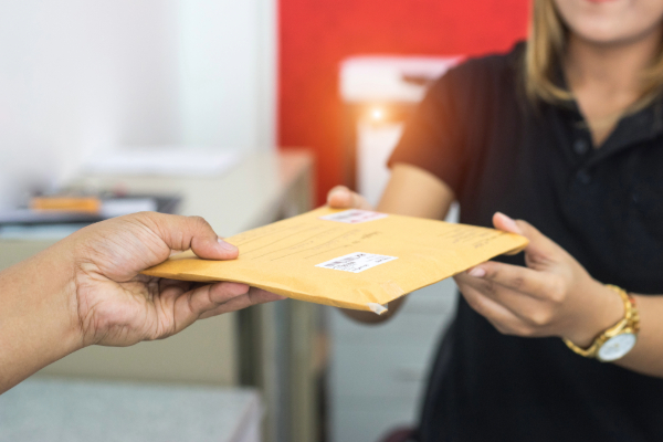 Person handing a woman a sealed envelope