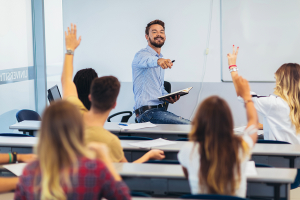 Male teacher sitting on desk calling on students