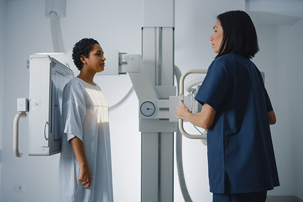 A patient being prepped for a breast screening by a nurse.