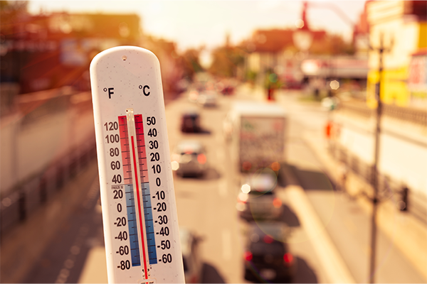 Thermometer in front of cars and traffic during heatwave
